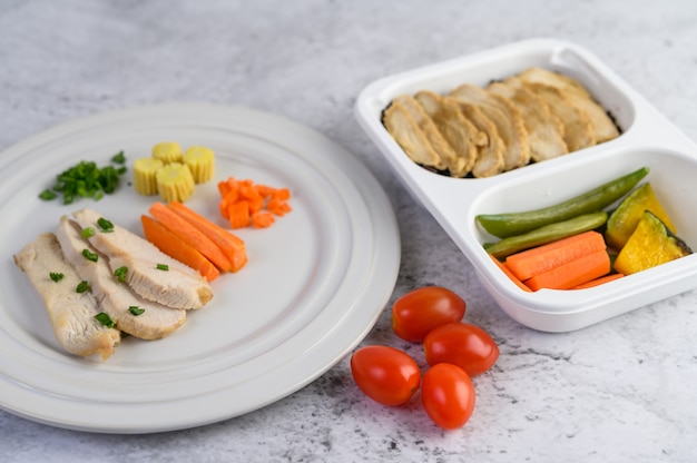 Petto di pollo al vapore su un piatto bianco con cipollotti e carote tritate