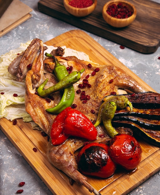 Petto di pollo grigliato in diverse varianti con pomodorini, pepe verde su una tavola di legno.