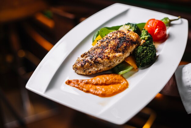 Petto di pollo grigliato vista laterale con verdure e salsa di broccoli