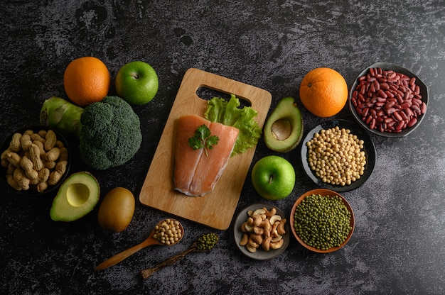 Pezzi di legumi, frutta e pesce salmone su un tagliere di legno.