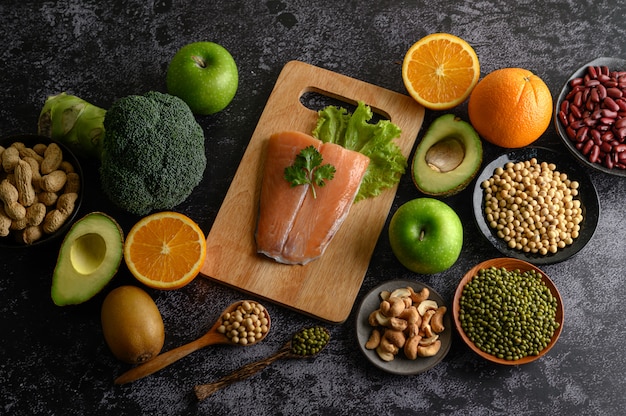 Pezzi di legumi, frutta e pesce salmone su un tagliere di legno.