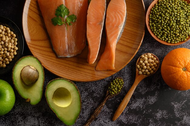 Pezzi di legumi, frutta e salmone su un piatto di legno.