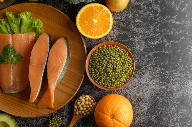 Pezzi di legumi, frutta e salmone su un piatto di legno.