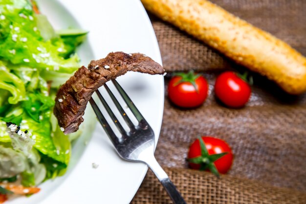 pezzo di insalata di carne sulla vista laterale folk tonato grissini