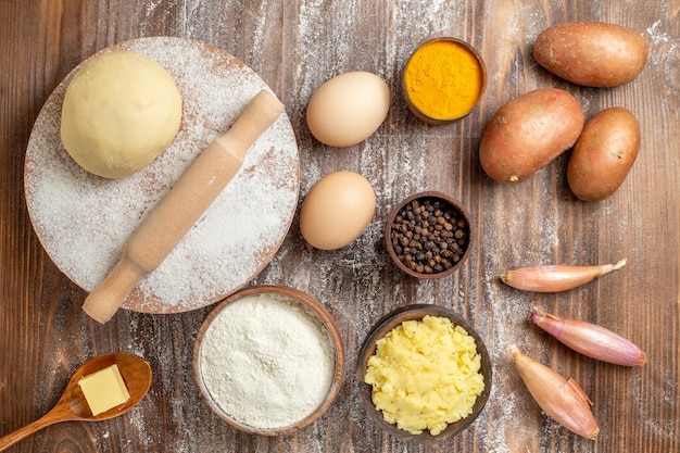 Pezzo di pasta cruda vista dall'alto con farina di patate e uova su farina di farina da scrivania in legno cuocere il colore dell'impasto