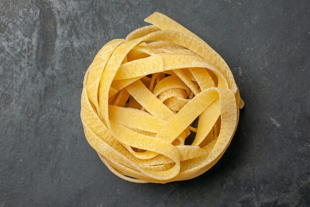 Pezzo di pasta lunga vista dall'alto arrotolato su sfondo scuro