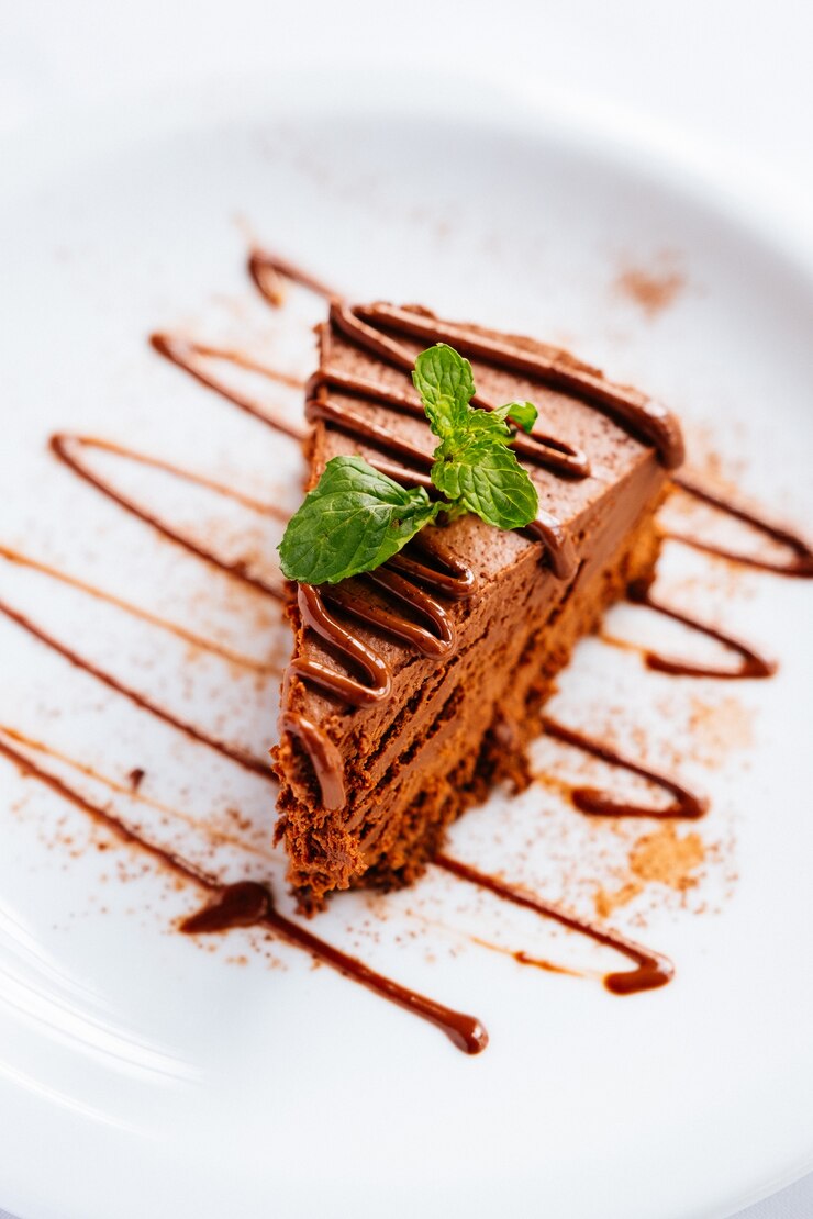Foto gratuito pezzo di torta al cioccolato con menta e topping al cioccolato sotto le luci con uno sfondo sfocato
