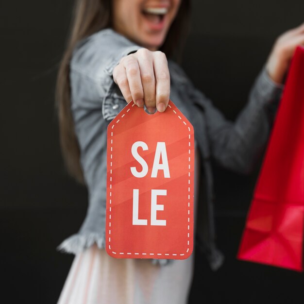 Piangere donna con il pacchetto dello shopping e segno di vendita