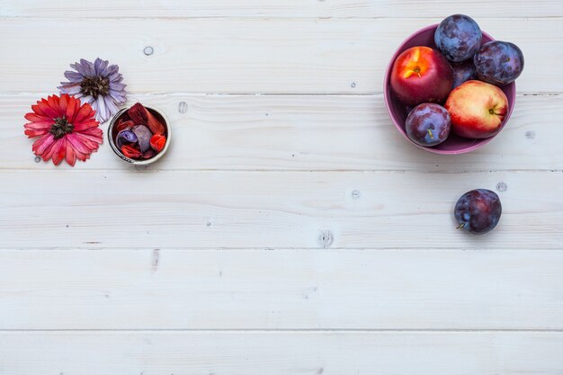 Piano del tavolo in legno con frutta fresca e fiori prugne e nettarine con spazio per il testo su di esso