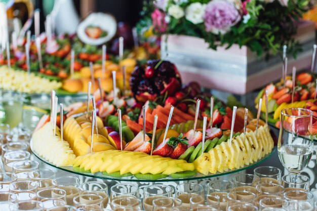 Piastra con fette di frutta esotica e bicchieri pieni di bevande alcoliche