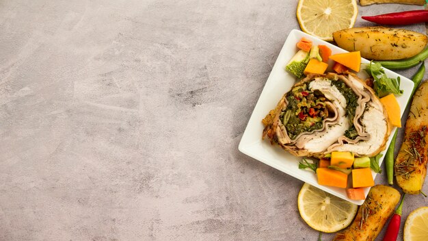 Piastra con rotolo di pollo e verdure sul tavolo di cemento