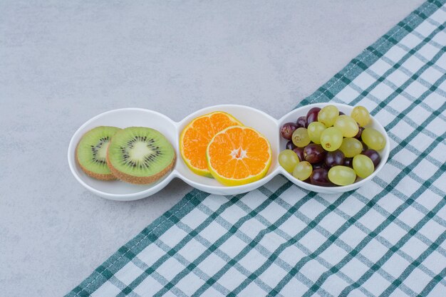 Piatti bianchi di frutta fresca sulla tovaglia. Foto di alta qualità