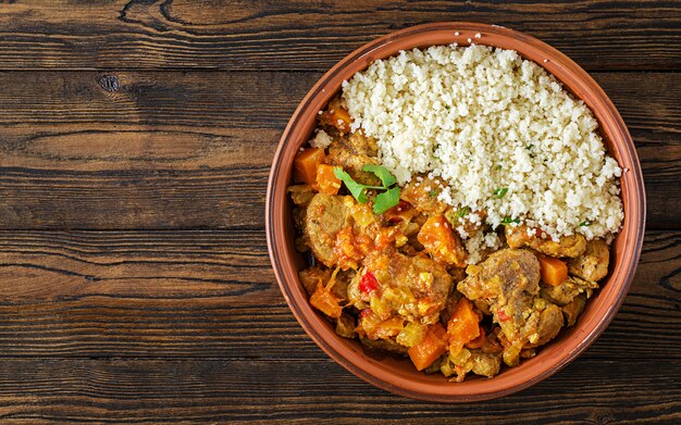 Piatti tradizionali tajine, couscous e insalata fresca sul tavolo di legno rustico. Tagine carne di agnello e zucca. Vista dall'alto. Disteso