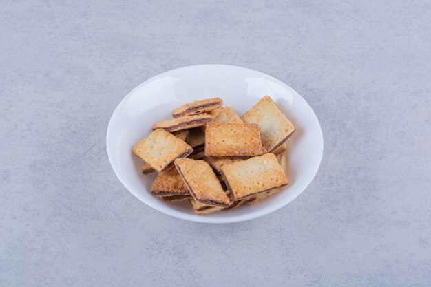 Piatto bianco di gustosi cracker croccanti sul tavolo di pietra.