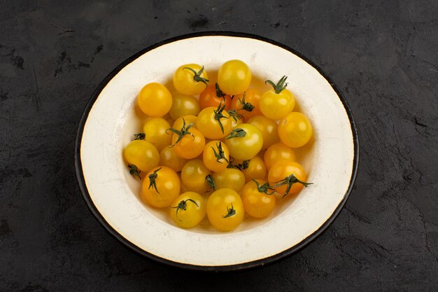 Piatto bianco interno fresco dei pomodori gialli su un gray