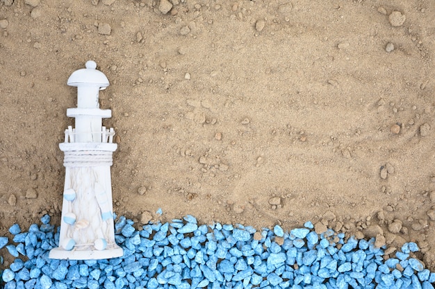 Piatto ciottoli blu con faro sulla sabbia
