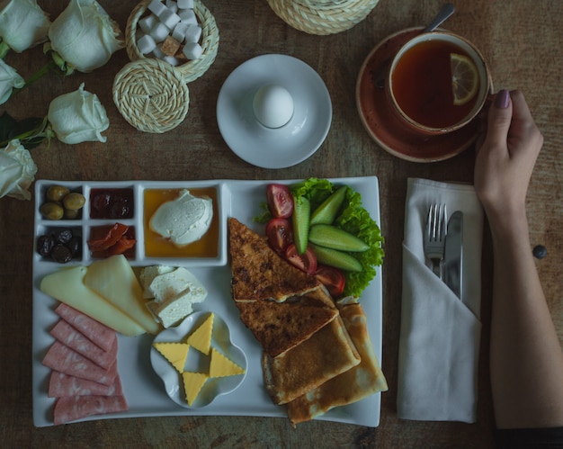 Piatto del menu della colazione con ampia selezione di cibi e tazza di tè