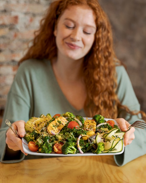 Piatto della holding della donna del colpo medio con il cibo