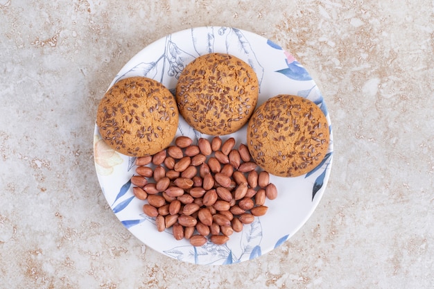 Piatto di biscotti di farina d'avena e noccioli di arachidi sulla superficie di marmo.
