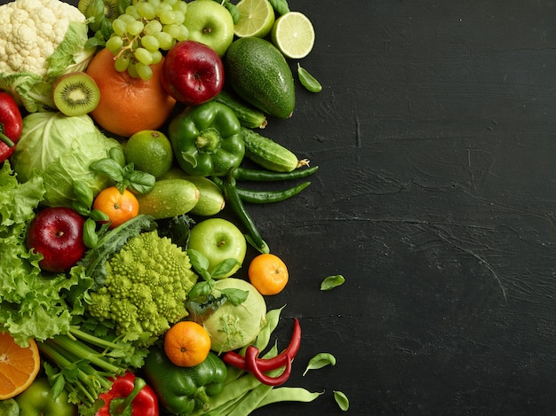 Piatto di cibo sano su sfondo di pietra nera. Set salutare che include frutta e verdura. Uva, mela, kiwi, pepe, lime, cavolo cappuccio, zucchine, pompelmo. Una corretta alimentazione o menu vegetariano.