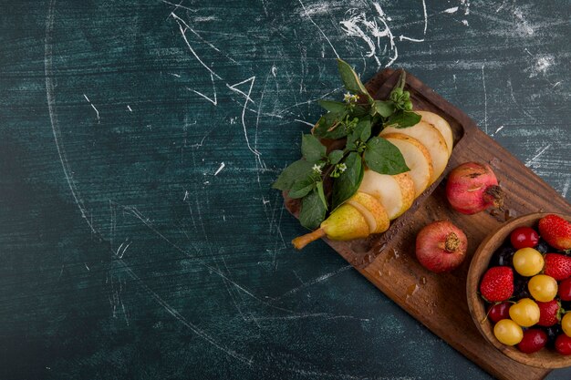 Piatto di ciliegie con melograno e pere su un piatto di legno nell'angolo