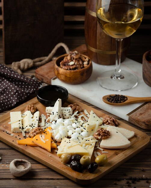 piatto di formaggi su tavola di legno con vino bianco