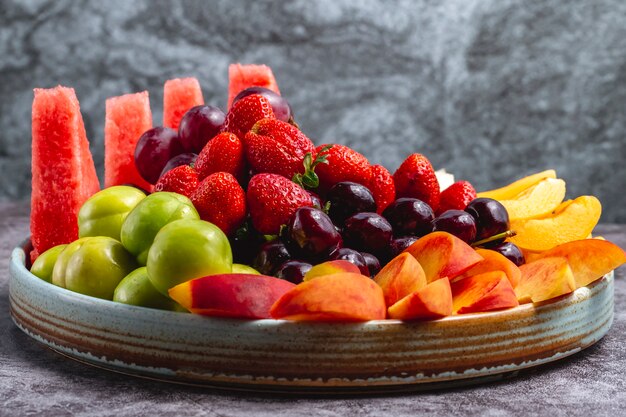 Piatto di frutta con anguria greengage prugna uva pesca albicocca fragola melone e ciliegia