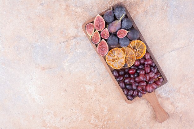 Piatto di frutta con fichi viola, arance e bacche di corniolo.