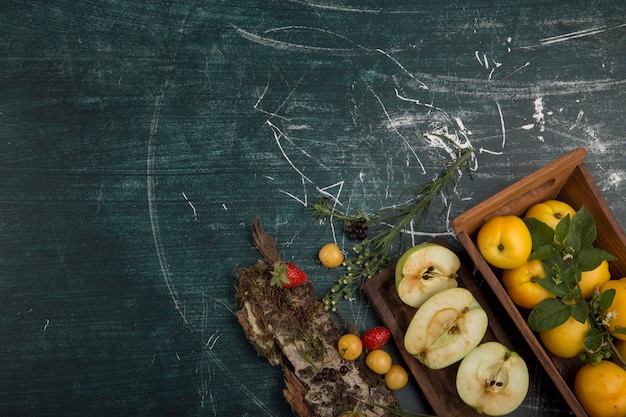 Piatto di frutta rotondo con pere, mele e frutti di bosco su sfondo opaco, nell'angolo