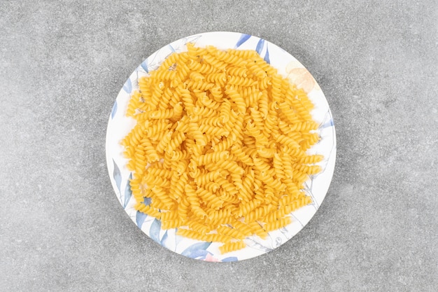 Piatto di fusilli crudi su superficie in marmo