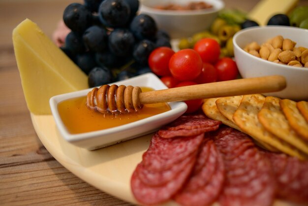 Piatto di gustosi snack: formaggio, cracker, miele, frutta e noci