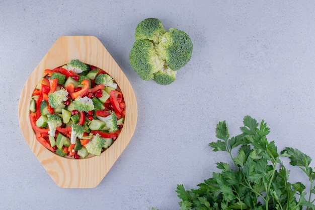 Piatto di insalata con fasci di broccoli e foglie di prezzemolo su sfondo marmo.