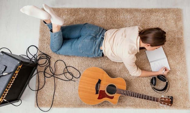 Piatto di laici musicista a casa a scrivere canzoni con cuffie e chitarra acustica