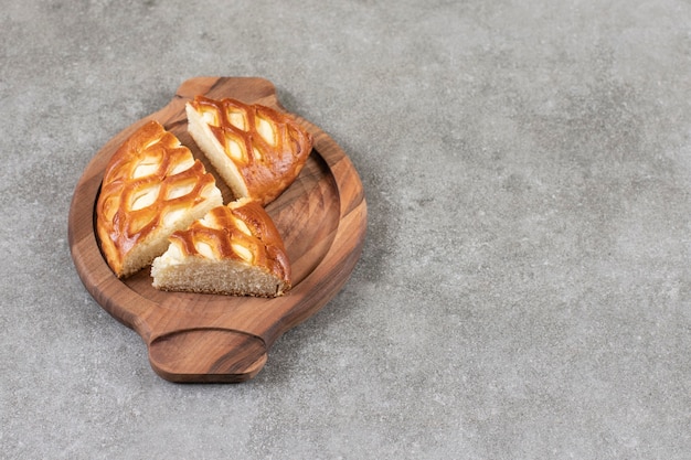 Piatto di legno di gustosa torta a fette sulla superficie in marmo.