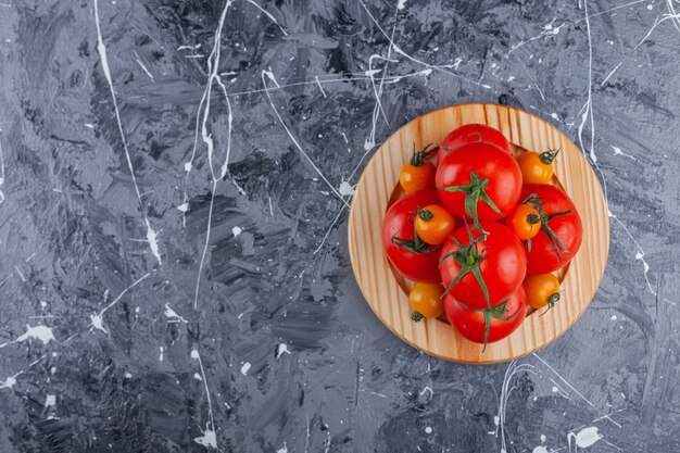 Piatto di legno di pomodorini e pomodori rossi sulla superficie in marmo