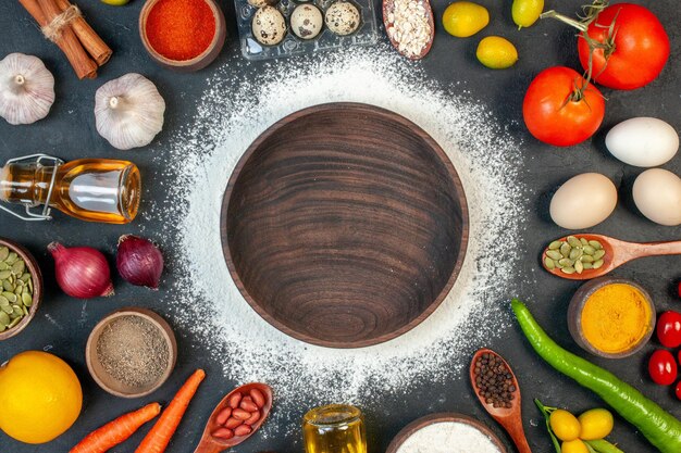 Piatto di legno marrone con vista dall'alto con uova di verdure e condimenti su sfondo scuro torta di zucchero colore bianco tè biscotto biscotto insalata cibo