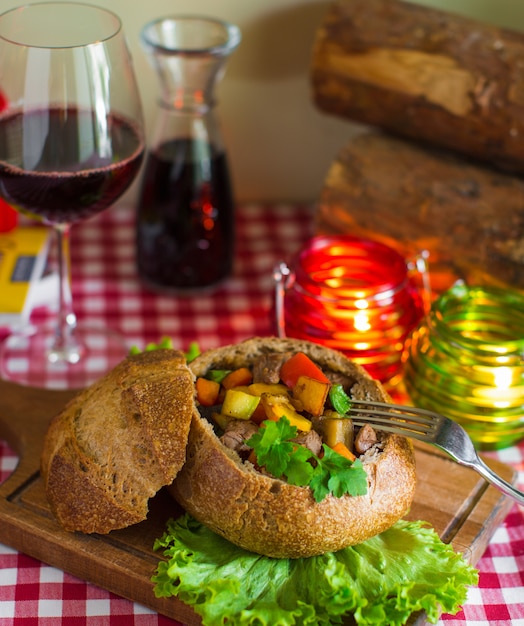 Piatto di manzo arrosto con patate, carote e pepe in una ciotola di pane