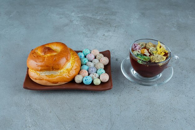 Piatto di pasticceria e caramelle con tazza di tè su marmo.