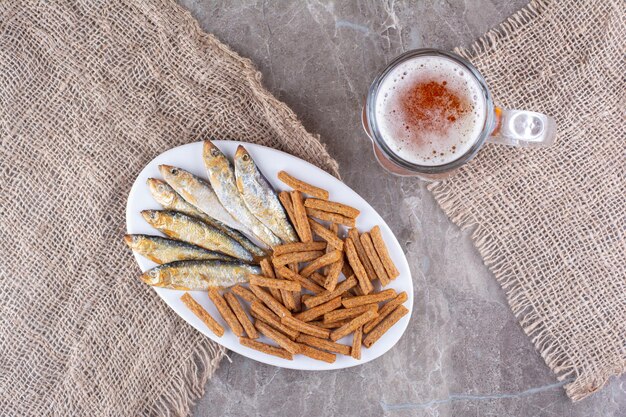 Piatto di pesce e cracker con birra sulla superficie in marmo