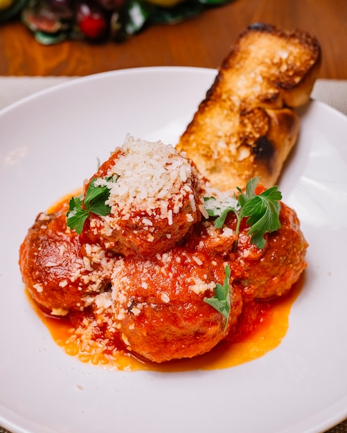 Piatto di polpette guarnito con salsa di pomodoro grattugiato e prezzemolo verticale