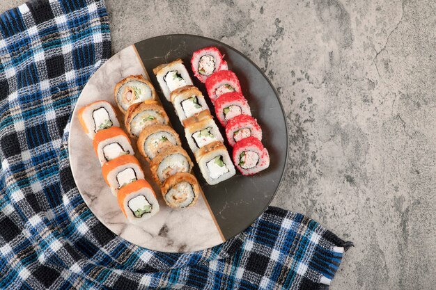 Piatto di vari deliziosi involtini di sushi sul tavolo di marmo