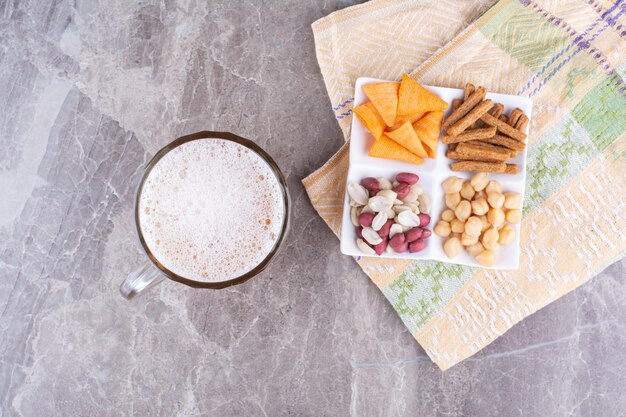 Piatto di varietà di snack e birra sulla superficie di marmo. Foto di alta qualità