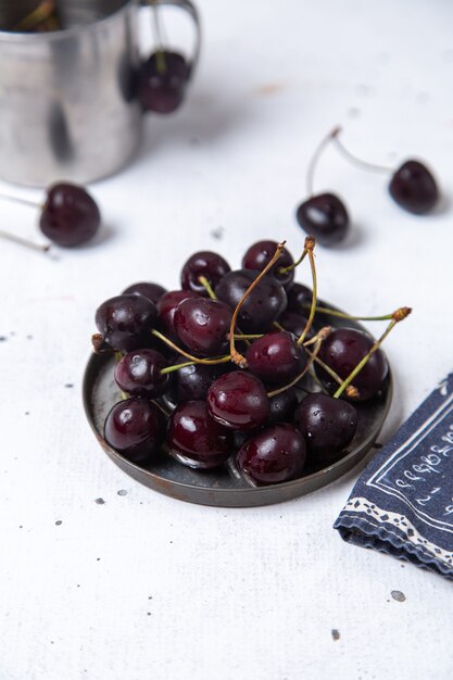 Piatto di vista frontale con ciliegie fresche aspre e pastose su grigio