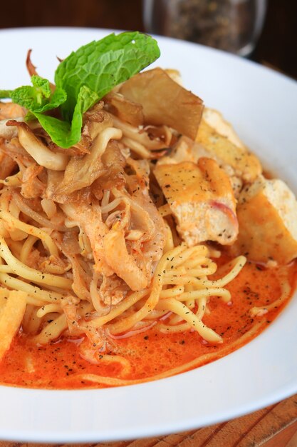 Piatto di zuppa con spaghetti, pezzi di pane e decorato con verdure