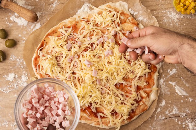 Piatto disteso a mano spolverata di prosciutto sulla pasta della pizza
