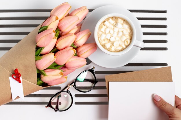 Piatto disteso della tazza di marshmallow con tulipani e bicchieri