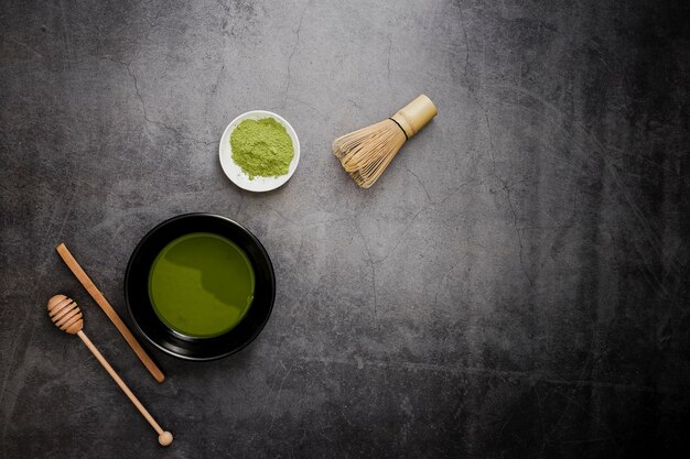 Piatto disteso di tè matcha con frusta di bambù e mestolo di miele