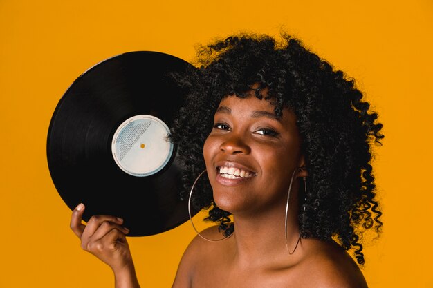 Piatto etnico felice del vinile della tenuta della donna su fondo luminoso