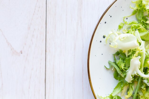 Piatto in ceramica bianca con insalata fresca su una superficie di legno