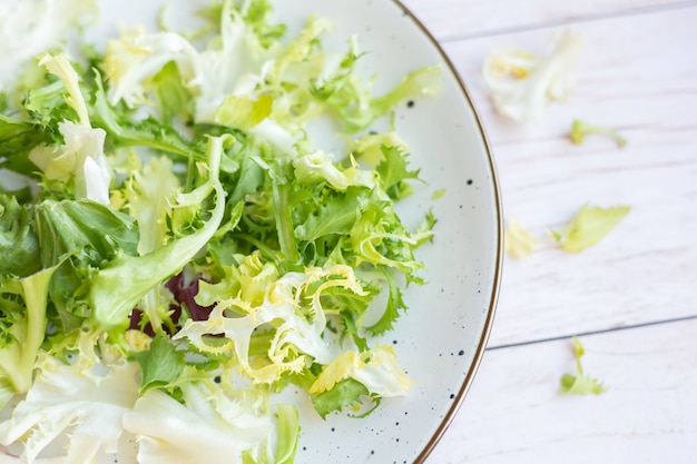 Piatto in ceramica bianca con insalata fresca su una superficie di legno